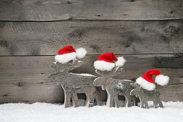 Red reindeer wearing a santa hat on grey wooden.