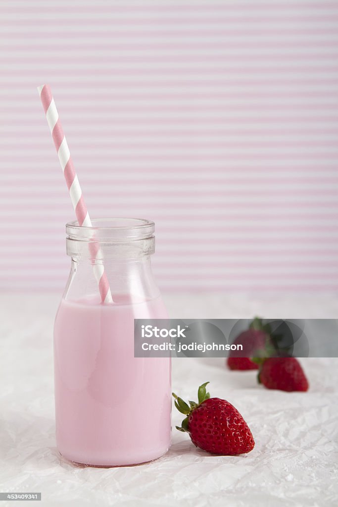 Strawberry milk in retro bottle vertical Strawberry milk in retro bottle vertical with striped straw and background Bottle Stock Photo