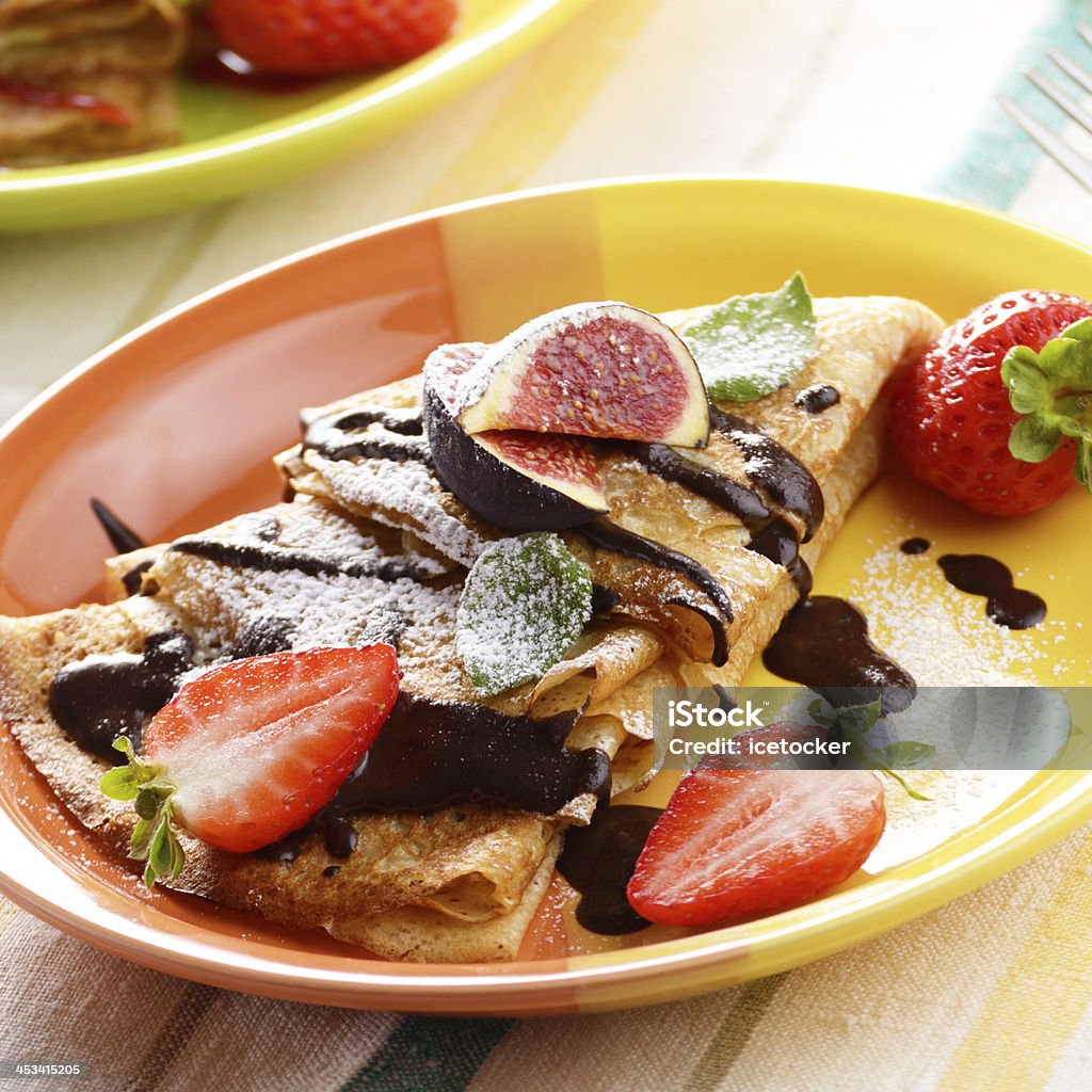 Strawberry crepes Strawberry crepes with chocolate syrup, figs and mint on the table Chocolate Sauce Stock Photo