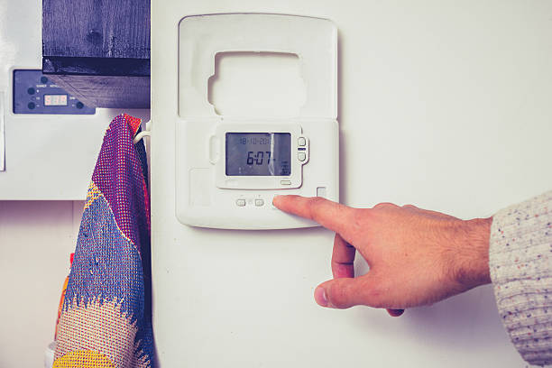 mão pressionando o botão de controles de aquecimento central - thermostat dial human hand white - fotografias e filmes do acervo
