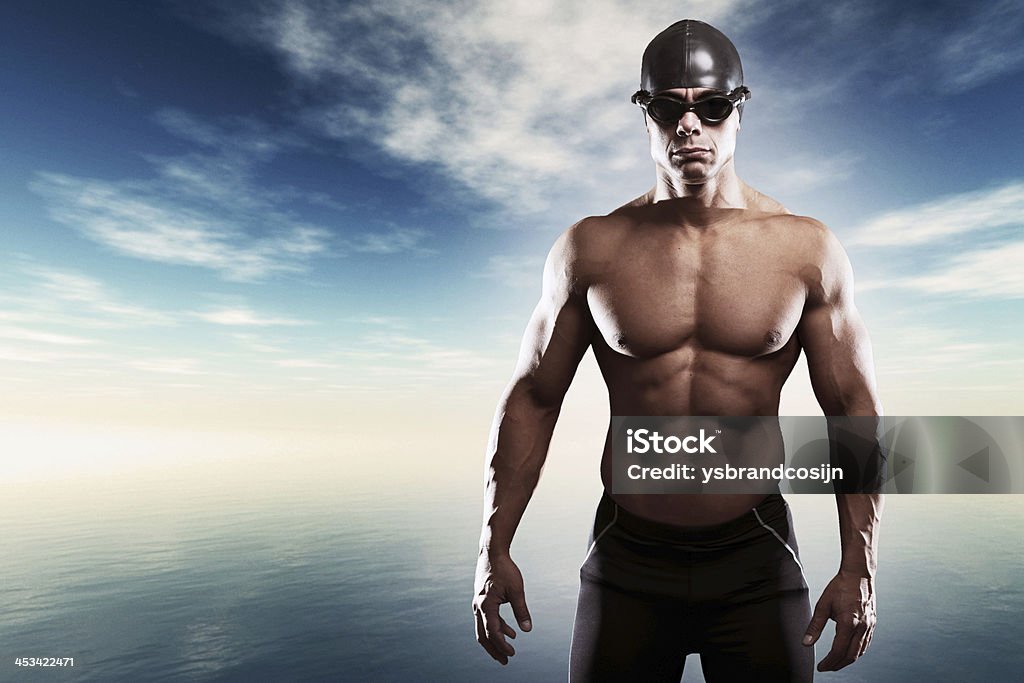 Muscled swimmer man with cap and glasses. Muscled swimmer man with cap and glasses outdoor at a lake with blue cloudy sky. Extreme fitness sport. Active Lifestyle Stock Photo