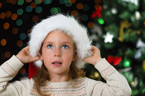 istock Little girl in santa's hat over christmas tree 453425095