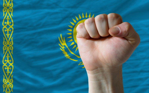 complete national flag of kazakhstan covers whole frame, waved, crunched and very natural looking. In front plan is clenched fist symbolizing determination