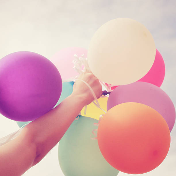 istock Hand holding colorful balloons filtered with a retro effect 453438609