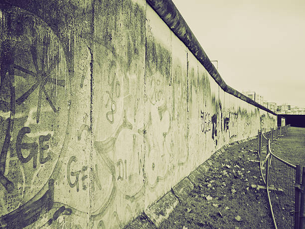 Panoramic view of famous Berlin Wall decorated with colorful graffiti street art at historic East Side Gallery on a moody cloudy day with retro vintage pastel toned filter effect, Berlin, Germany