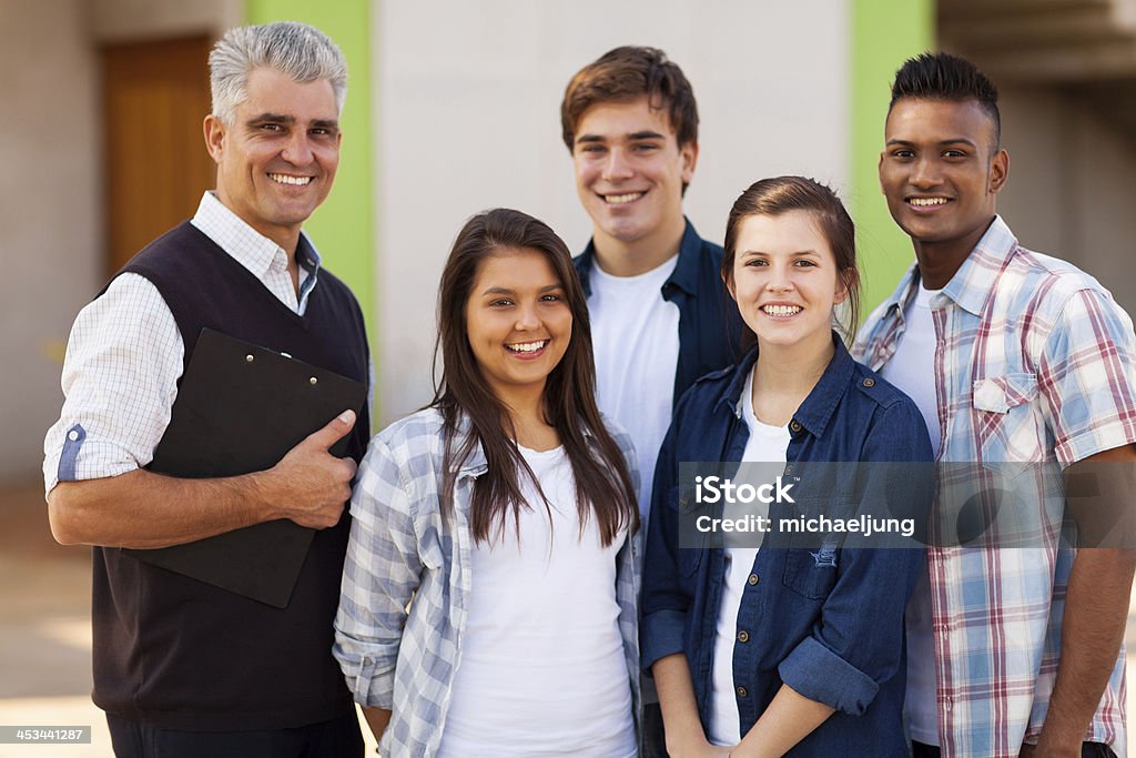 male high school teacher standing with students cheerful male high school teacher standing with students outdoors Group Of People Stock Photo