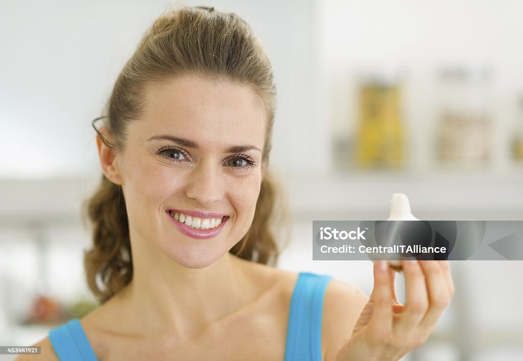 Smiling young housewife showing garlic Adult Stock Photo