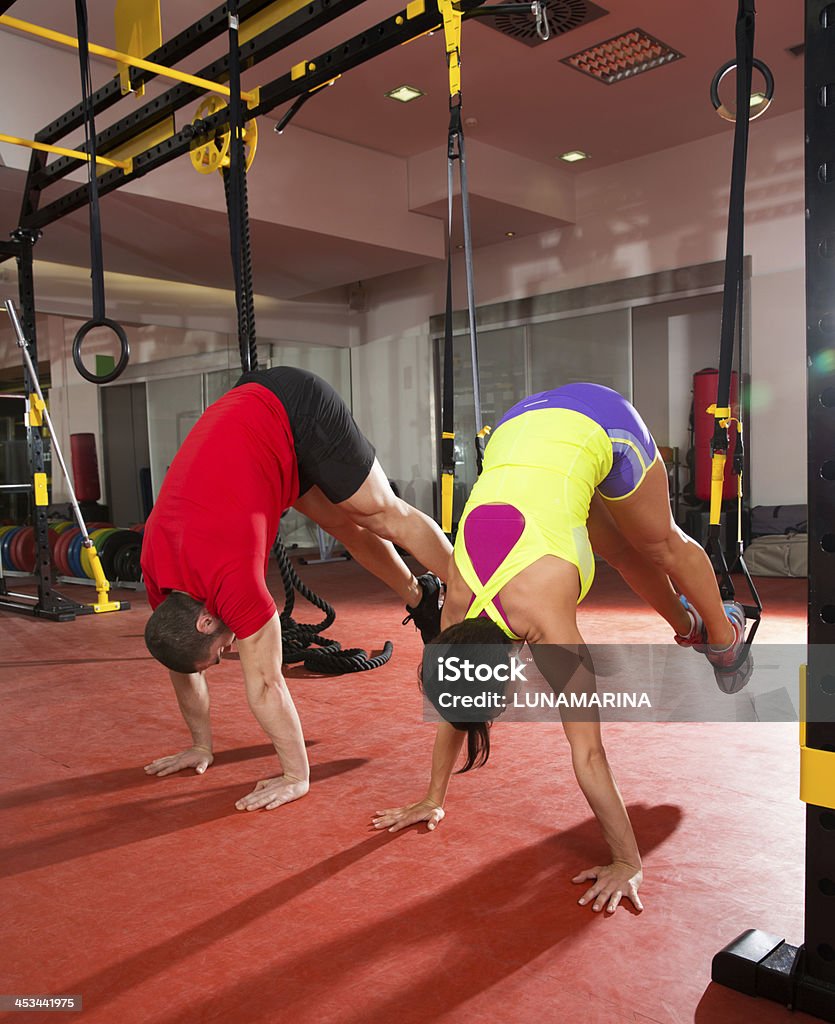 Esercizi di allenamento TRX Fitness presso la palestra donna e uomo - Foto stock royalty-free di Andare giù
