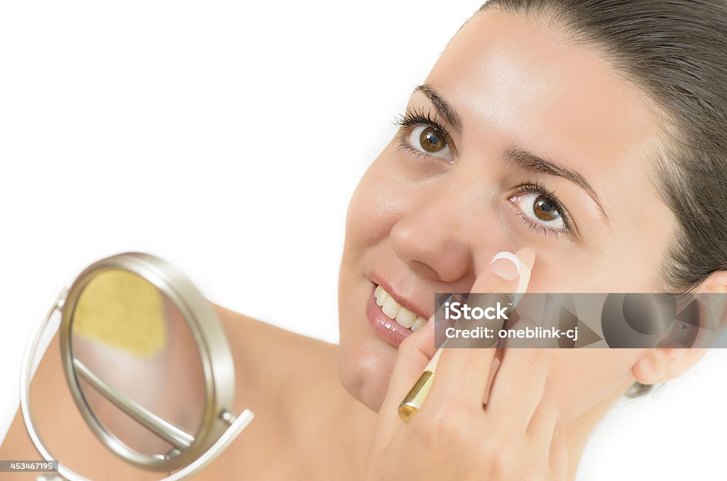 Woman Using Concealer Young woman using concealer looking in the mirror Periorbital dark circles Stock Photo