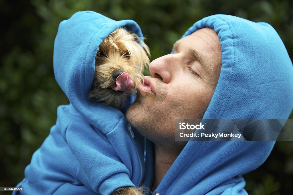 Homme Embrasser meilleur ami chien Bleu assorti sweats à capuche au Park - Photo de Chien libre de droits