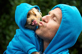 Man Kissing Best Friend Dog Matching Blue Hoodies at Park