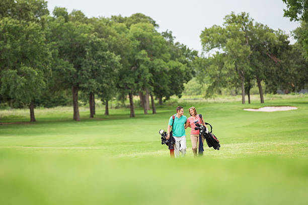 istock Couple carrying clubs walking on golf course together 453469493