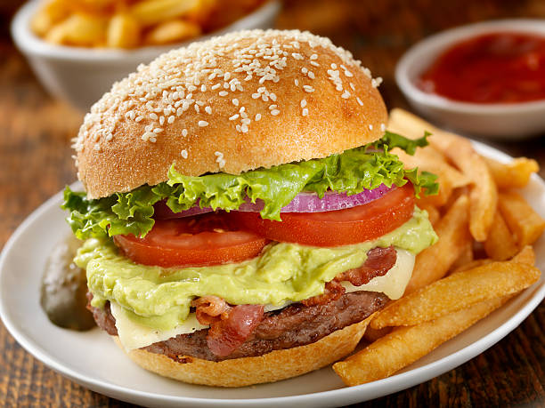 A cheeseburger with white cheddar, guacamole, lettuce and tomato with a side of crosscut fries