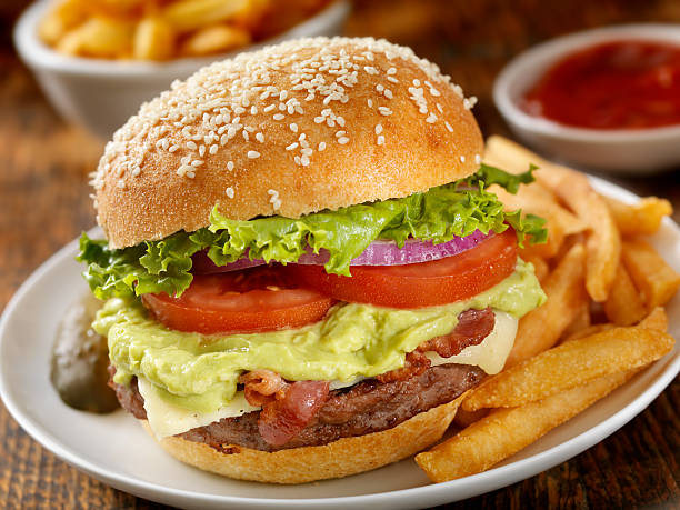 The Guacamole Bacon Burger The Guacamole Bacon Burger with Lettuce, Tomato, Red Onion, Cheese and Fries-Photographed on Hasselblad H3D2-39mb Camera bacon cheeseburger stock pictures, royalty-free photos & images