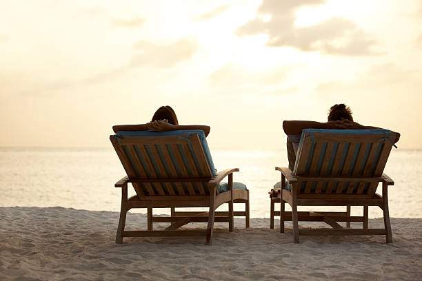 istock Couple sitting on chairs at the beach enjoying sunset 453469721
