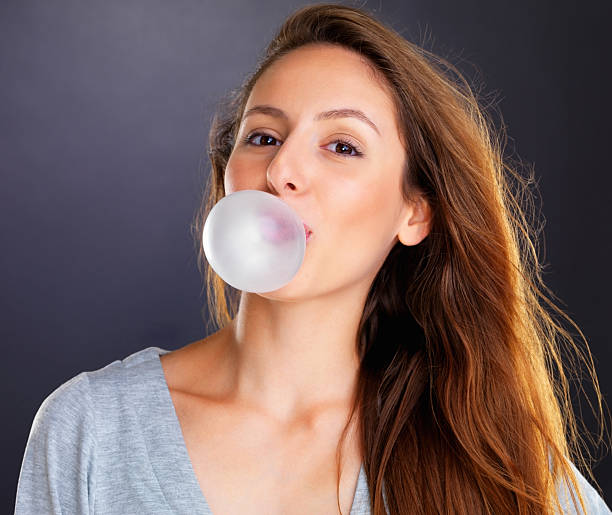 istock Woman blowing a bubble with bubble gum 453471533