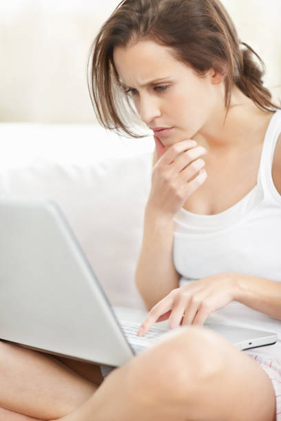 istock Confused young female working on a laptop at home 453472345