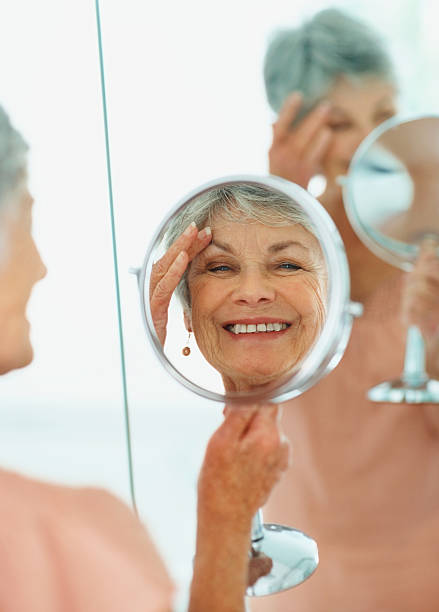 istock Happy senior woman looking at herself in a handheld mirror 453472575