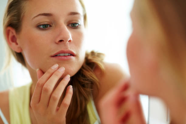 istock Cute young woman looking her face in the mirror 453472583