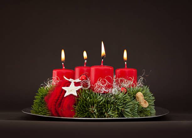 Advent wreath with fir branches on plate - Adventskranz Advent wreath with fir branches on plate with dark background advent candle wreath adventskranz stock pictures, royalty-free photos & images