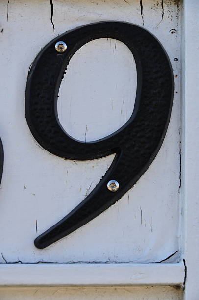 Street address black number 9 on white background with screws stock photo