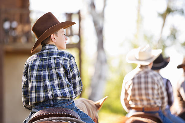 istock Little cowboy riding horse during ranch trail ride 453491157