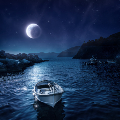 Night paradise. Shot of boat against full moon and starry sky.