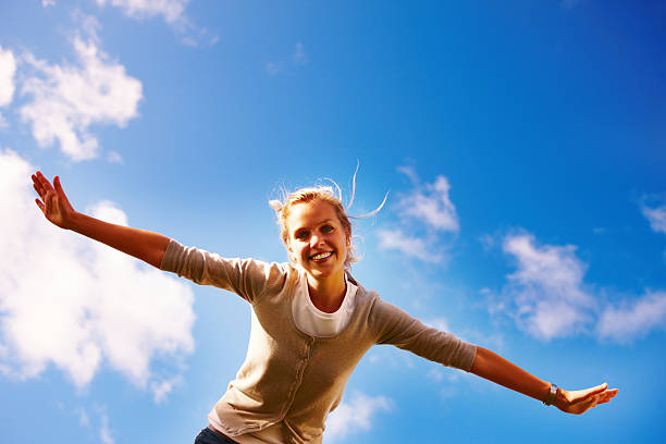 istock Female spreading her arms under the open blue sky 453494265