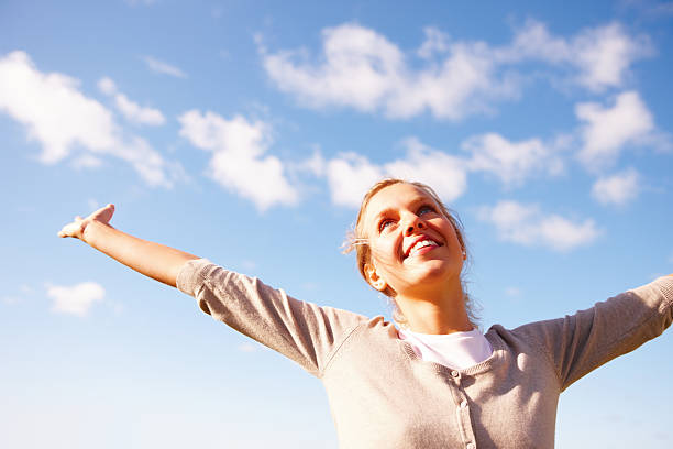 istock Young female spreading her arms under the open sky 453494363