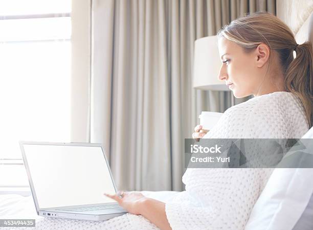 Felice Donna Seduta Sul Letto Utilizzando Un Computer Portatile - Fotografie stock e altre immagini di Adulto