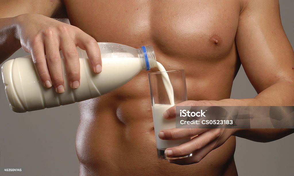 Diet milk. Strong and fitness man pouring milk glass. Abdomen Stock Photo