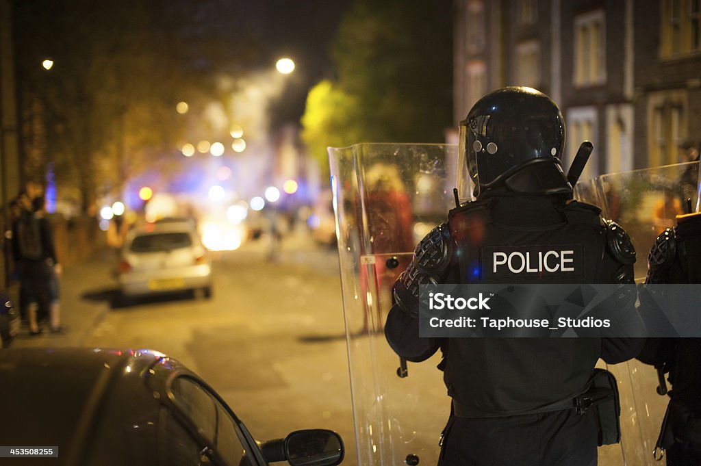 Police defending riot Riot police move forwards towards burning waste bins and rioting. Riot Stock Photo