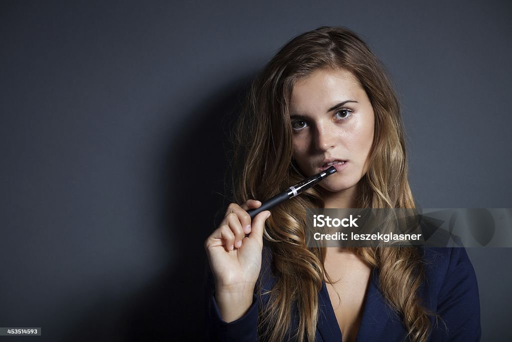 Elegant woman with e-cigarette wearing suit Elegant woman with e-cigarette, wearing suit Addiction Stock Photo