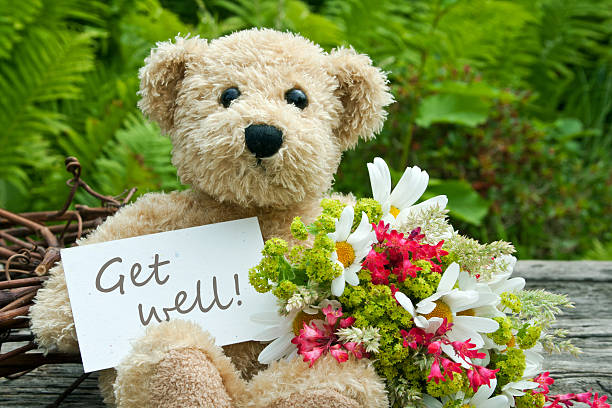 Get well soon teddy bear with flowers teddy bear with flowers and card with lettering get well get well soon stock pictures, royalty-free photos & images