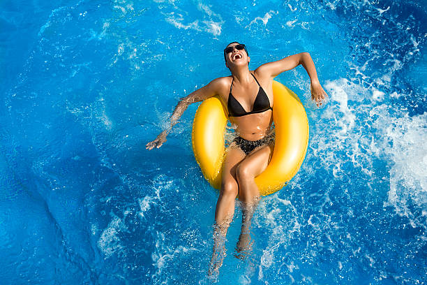 aquapark. schönheit brunette. spaß im pool - swimming pool women floating on water bikini stock-fotos und bilder