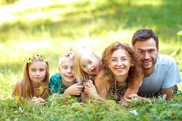счастливая семья с тремя детьми - glasses grass women lying on front стоковые фото и изображения