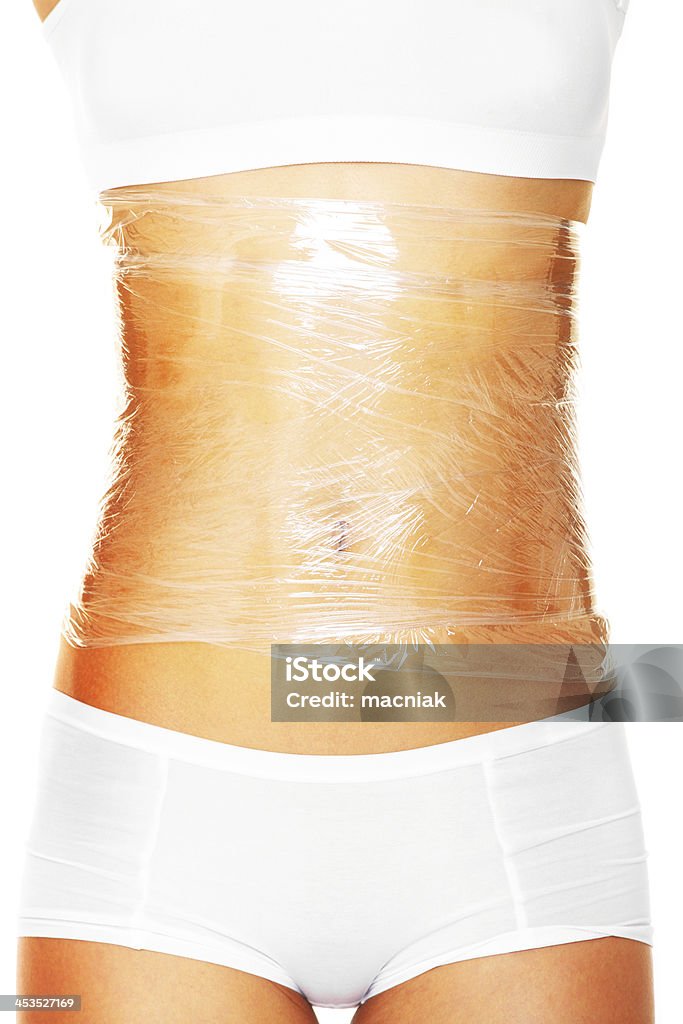 Cellulite therapy A picture of a sexy female body wrapped around with foil to reduce cellulite over white background Abdomen Stock Photo