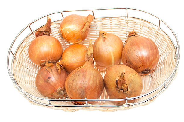 istock Fresh golden onions in a wicker plate, isolated 453531095