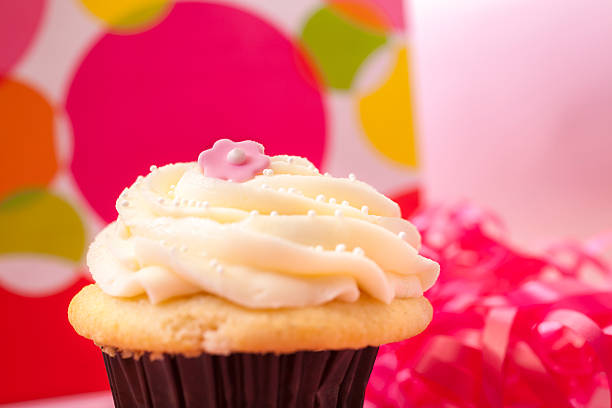 Food:  Pastel cupcake with gift and ribbon in background.