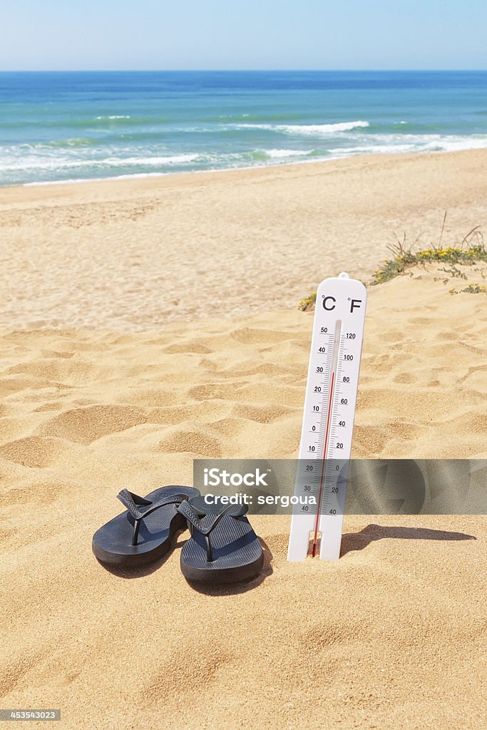 Pantoufles sur la plage à côté de Thermomètre et la mer. - Photo de Bleu libre de droits