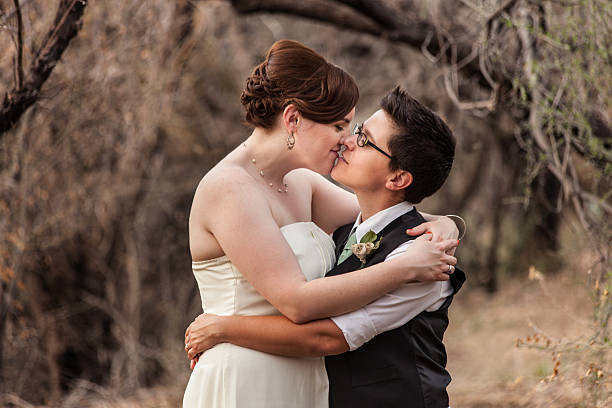 Lesbian Couple Kissing in the Woods Happy same sex newlyweds kissing in the woods gay wedding kiss stock pictures, royalty-free photos & images