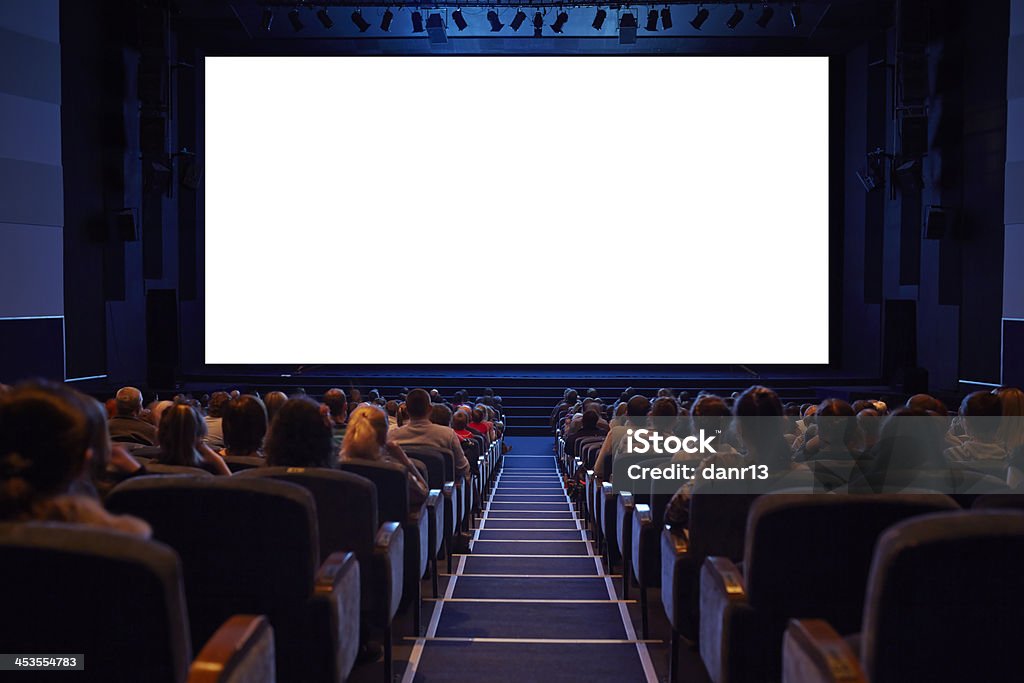 Empty cinema screen with audience. Empty cinema screen with audience. Ready for adding your picture. Screen has crisp borders. This shot was made using tripod with long exposure. Movie Theater Stock Photo