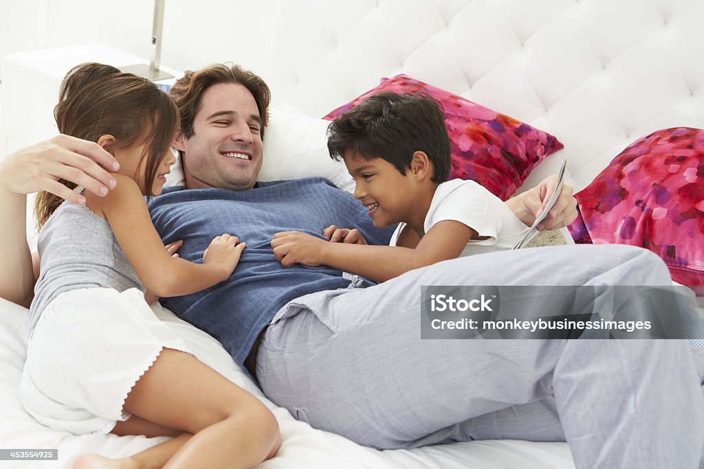 Pai e filhos relaxante na cama juntos - Foto de stock de 20 Anos royalty-free