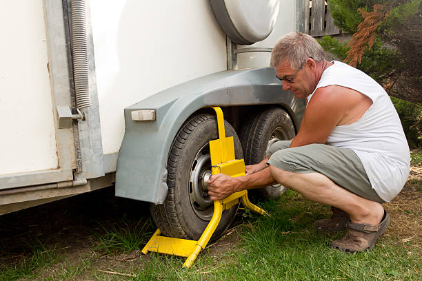 Safe and secure Man fits wheel lock to horse box to ensure its safety whilst parked. car boot stock pictures, royalty-free photos & images