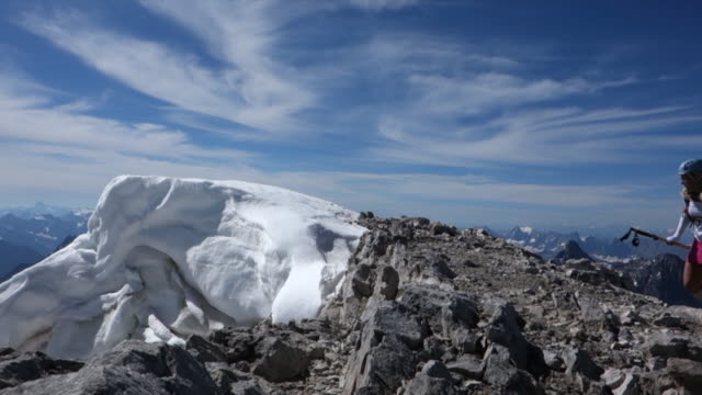 Mountaineers walk along summit ridge, above surrounding mountains
