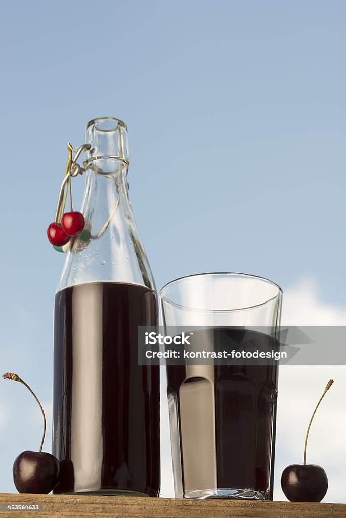 Cherry juice Kirschsaft Homemade cherry juice with some cherries around against blue sky. Blue Stock Photo