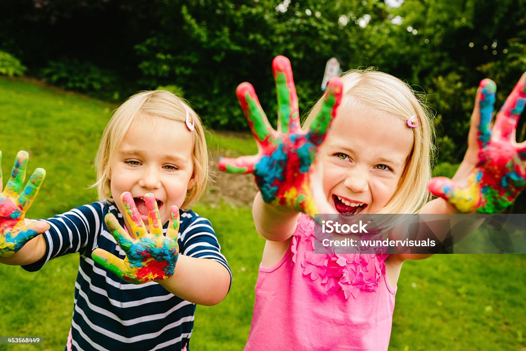 Cute sisters having fun with finger paint Little girls painting with finger paint Child Stock Photo