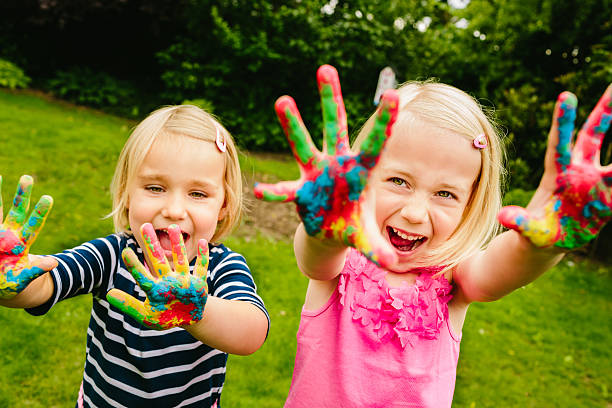 linda irmãs se divertindo com pintura a dedo - happiness cheerful family schoolyard - fotografias e filmes do acervo