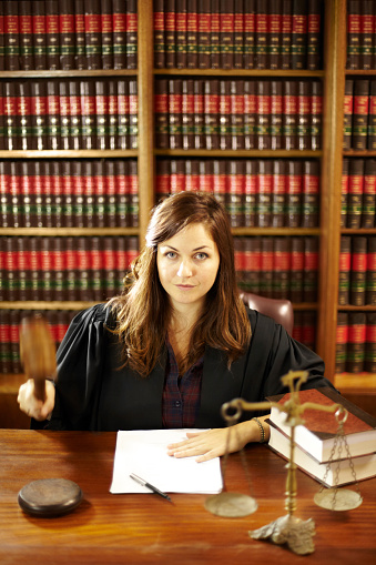 Serious young judge using her gavel in her offices while working