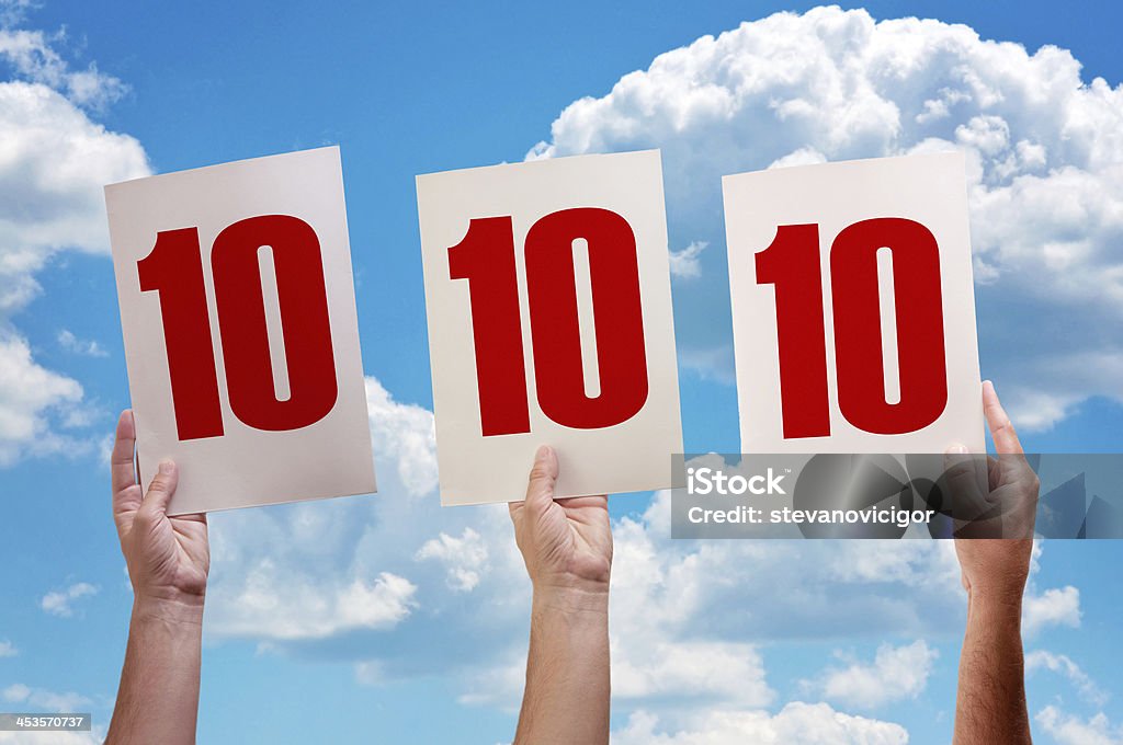 Best grade Best grades. Number ten on white paper held by three male hands raised in air. Blue sky in background. Number 10 Stock Photo